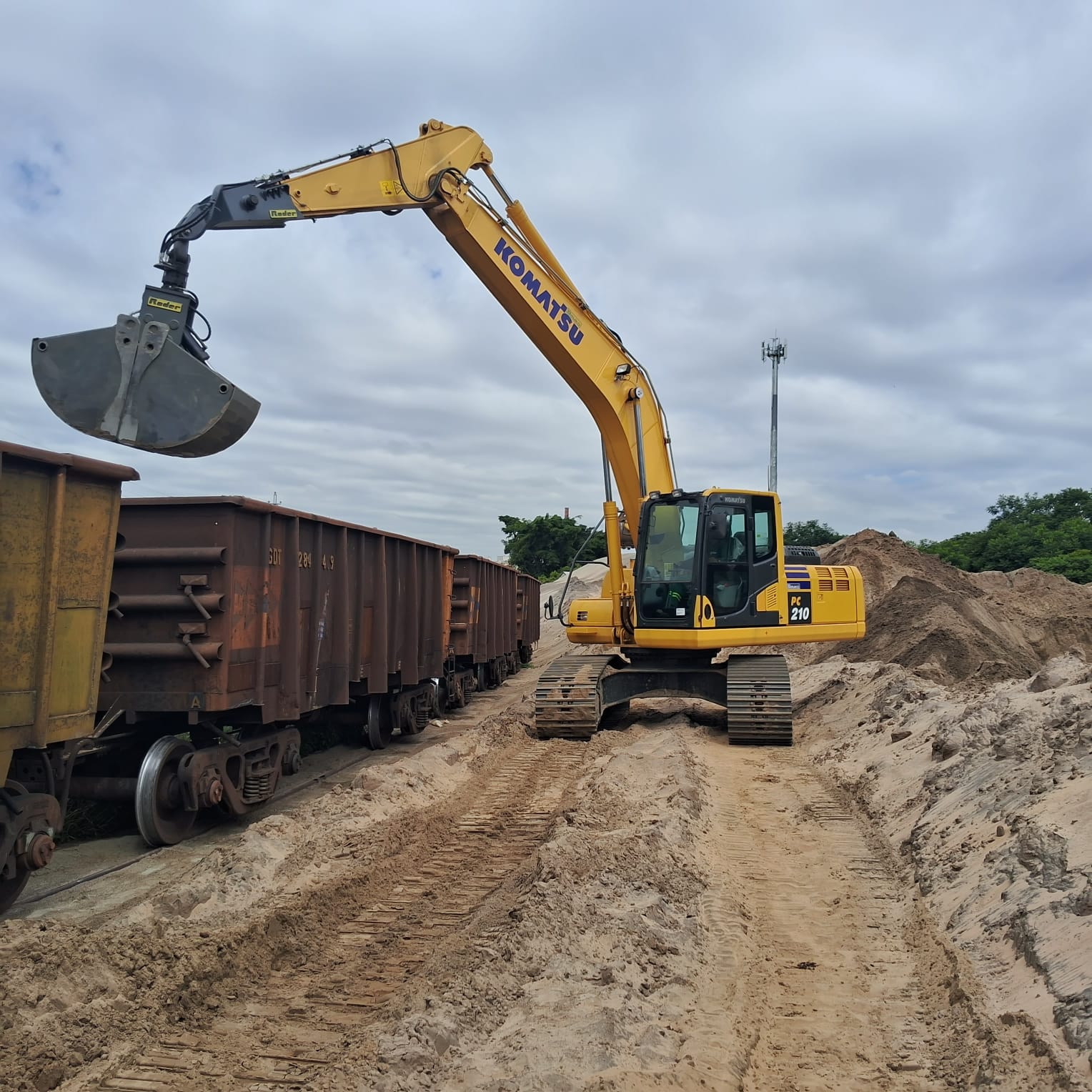 Escavadeira_hidráulica_com_caçamba_clamshell_realizando_descarregamento_de_areia_em_vagões_ferroviários